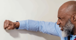 Man punches wall, depicting frustration with alcohol intake while on antidepressants. Managing alcohol on antidepressants concept.