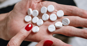 White pills on a hand, illustrating how long methamphetamine stays in your system for drug tests and potential addiction concerns.