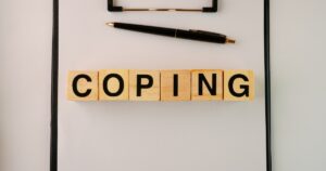 - Visalia Recovery Center Blocks spelling COPING on a clipboard with a pen above, suggesting coping strategies for mental health.